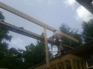 Carpenter setting a ridge beam over a new addition frame — Ice Dam Removal by Roofing Brothers in Haslett