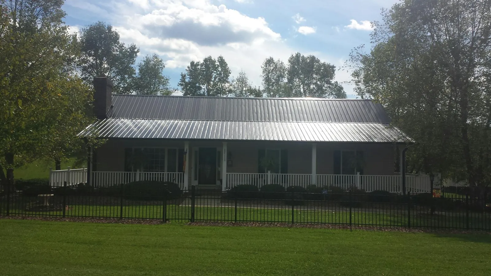 Gray metal roof on a brick ranch with a full width front porch — Gutter Guard Installation work by our crew in Haslett